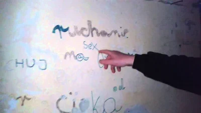 Mężczyzna pokazuje palcem na napis ruhanie na ścianie.
